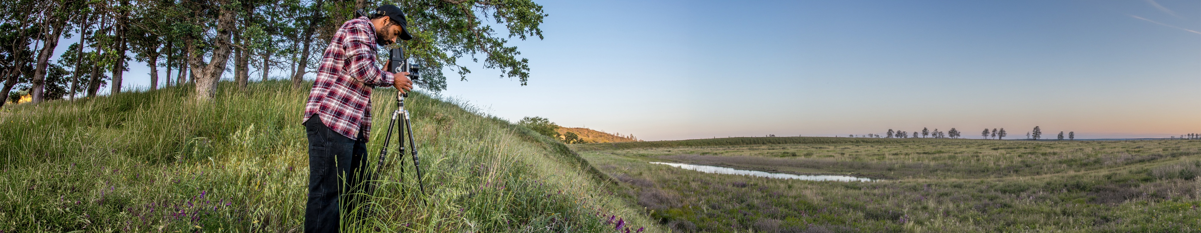 A researcher using a tripod beside a wetland